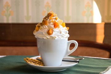 White cup of coffee with whipped cream and dried fruit.