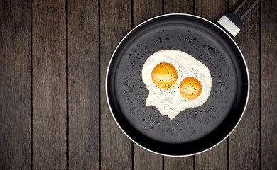 Skull fried egg on skillet on wooden background