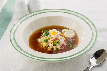 Summer cold soup okroshka with egg, radish, cucumber and dill served on the table
