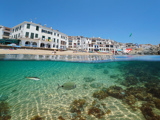 Fototapeta premium Spain Calella de Palafrugell Mediterranean village, beach shore with fish underwater sea, Costa Brava, Catalonia, split view half over and under water