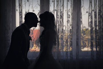 silhouette of bride and groom face to face. A man kisses a woman. Valentine's day