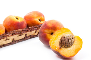 Whole and half of ripe peach fruit and several in basket isolated on white background.