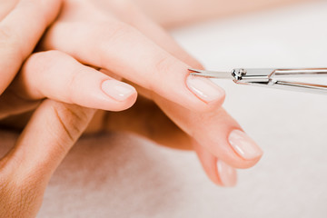 Obraz na płótnie Canvas Cropped view of manicurist using manicure scissors to remove cuticle
