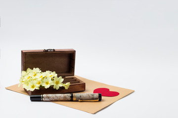 Wooden Vintage Casket, Envelope, Pen, Red Hearts of Cardboard and White Spring Flowers on a white background. The Concept of Letters and Love Memo