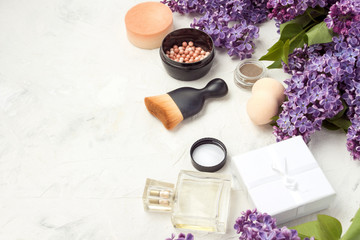 Accessories for make-up and skin care, perfumes, lilacs on a light stone background