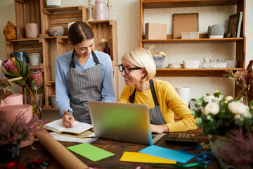 Portrait of two businesswomen using laptop while managing shop, copy space