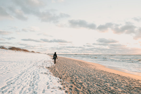 Woman walking on snow coast near sea