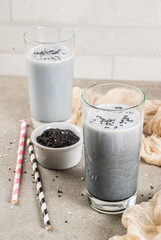 Trendy vegan food recipes, Black Sesame Iced Latte or smoothie with sesame seeds, dried coconut and Almond milk, grey stone table, copy space