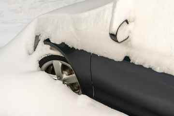 Car covered with snow during snowfall in the Parking lot