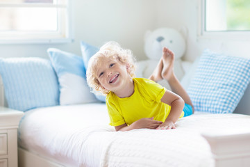 Child playing in bed. Kids room. Baby boy at home.