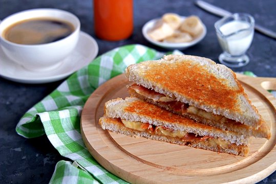 Sandwiches with peanut butter, banana and fried bacon on a wooden board.