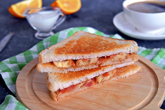 Sandwiches with peanut butter, banana and fried bacon on a wooden board.