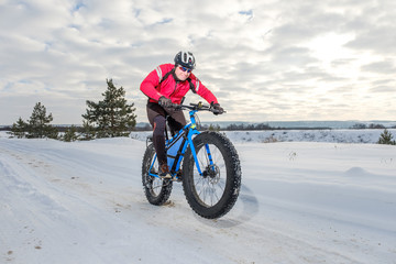 Fototapeta na wymiar A young man riding fat bicycle in the winter. Fat tire bike. 