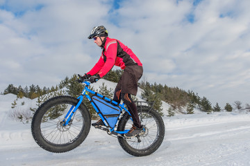 A young man riding fat bicycle in the winter. Fat tire bike.	