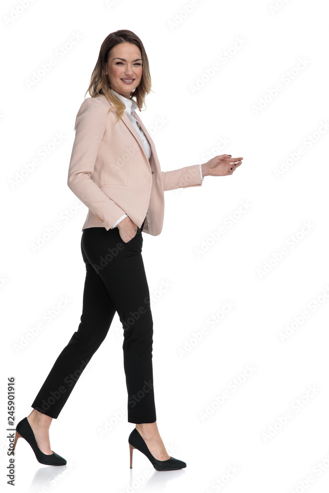 Poster side view of businesswoman walking with hand in pocket