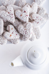 Fototapeta na wymiar Valentine's day white coconut heart shaped cookies with red and pink heart sprinkles. Copy space