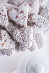 Fototapeta na wymiar Valentine's day white coconut heart shaped cookies with red and pink heart sprinkles. Copy space
