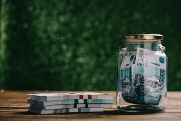 close-up view of glass jar with money and russian rubles banknotes on wooden table