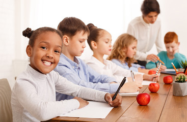 Children doing homework together with teacher at school