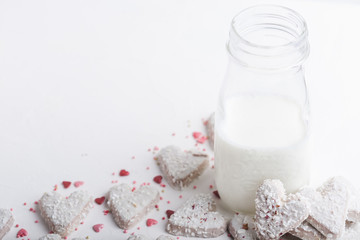  Valentine's day white coconut heart shaped cookies with red and pink heart sprinkles and milk bottle. Copy space