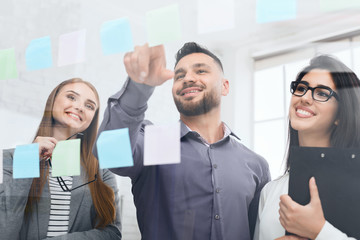 Businessman presenting ideas on sticky notes on glass wall
