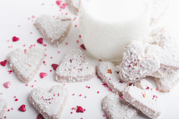  Valentine's day white coconut heart shaped cookies with red and pink heart sprinkles and milk bottle. Copy space