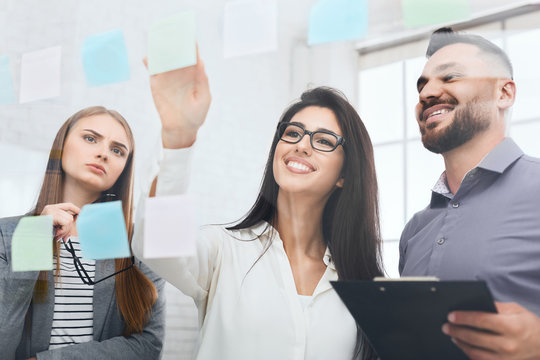 Woman brainstorming using adhesive notes on glass wall