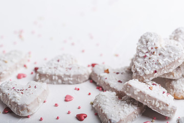  Valentine's day white coconut heart shaped cookies with red and pink heart sprinkles. Copy space