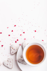  White tea cup with tea and Valentine's day white coconut heart shaped cookies with red and pink heart sprinkles. Copy space
