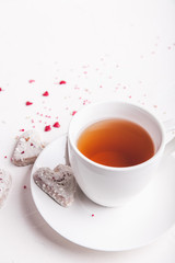  White tea cup with tea and Valentine's day white coconut heart shaped cookies with red and pink heart sprinkles. Copy space