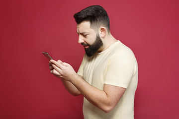 The young pretty cute brunette with a beard emotionally writes a message in the phone