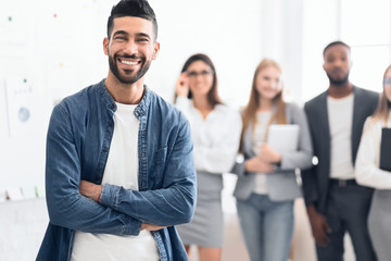 Man standing in office with colleagues on background