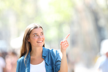 Happy girl pointing at side in the street a sunny day