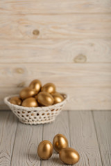 Happy easter! Easter eggs of golden color on a light wooden background.