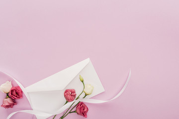 top view of flowers, ribbon and envelope isolated on pink with copy space