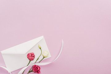 top view of flowers and envelope isolated on pink with copy space