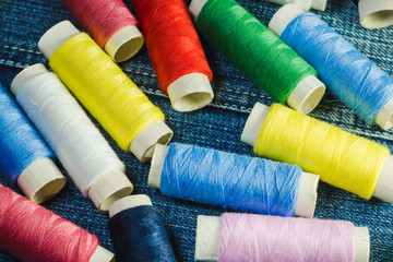 Spools of blue,white, pink, red and green sewing thread on blue denim
