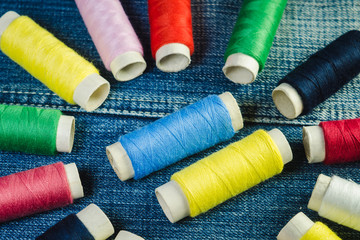 Spools of blue,white, pink, red and green sewing thread on blue denim