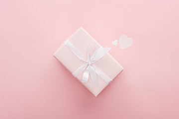 top view of gift box and paper hearts isolated on pink