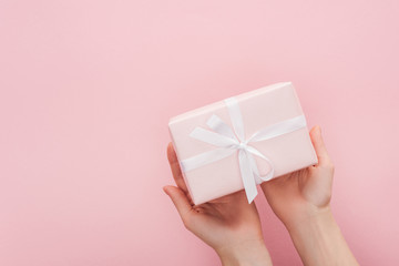 cropped view of woman holding gift box isolated on pink with copy space
