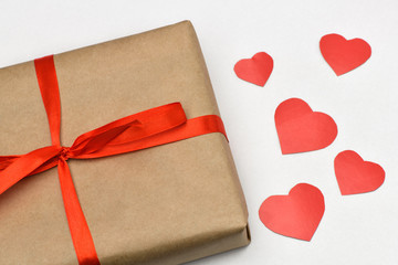 .Valentine's day. Gift box on a gray background in a Kraft brown package tied with a red ribbon on the right are cut five red. Horizontal photography.