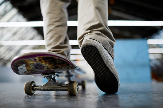 Skateboard moving forwards on flat surface with guy skateboarder leg pushing off the floor