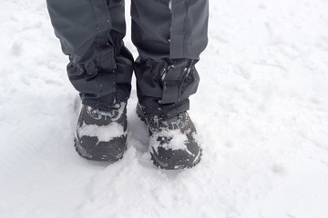 Women's legs in gray shoes and uppers in snow