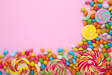 Fototapeta na wymiar Colorful lollipops and different colored round candy on pink background