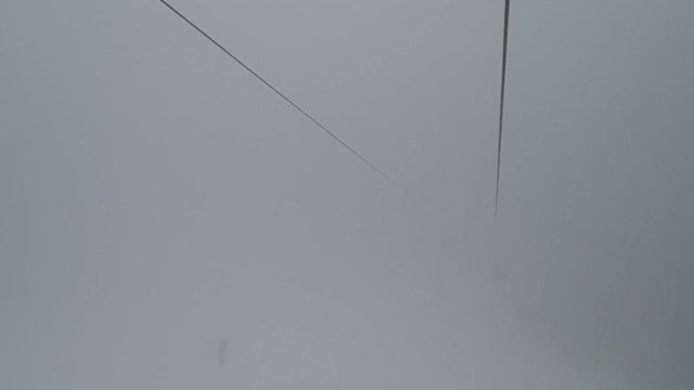 Footage of a chairlift on a mountain, with fog.