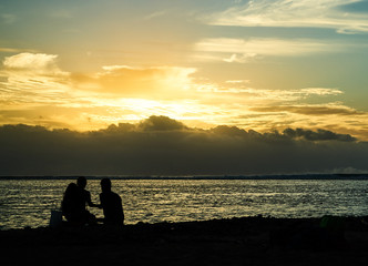 Three people having a sunset picknick on the beach in Black River, Mauritius