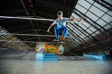 Skilled young sporptsman in activewear and helmet hanging in the air over skateboard while training at leisure
