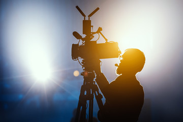 Cameraman silhouette on a live studio news stage.Professional cameraman with headphones in...