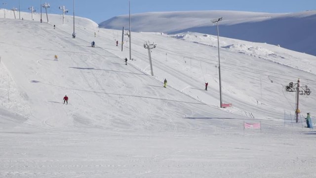 Ski resort in Khibiny. Skiers and snowboarders ascend on ski lift and go down the slope