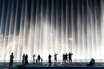Naklejka premium Sylwetki ludzi korzystających z pokazu fontann w Dubaju w nocy, Zjednoczone Emiraty Arabskie